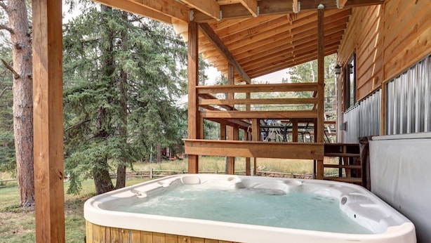 A wooden hot tub under a covered deck with a view of a forest. - Trail Mountain Cabin – Stunning Views, Hot Tub & Game Room (Lead)
