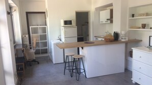 A compact kitchen with a central island, stools, a refrigerator, and a microwave. - Meltime Share Mélanie's living space (Nîmes)