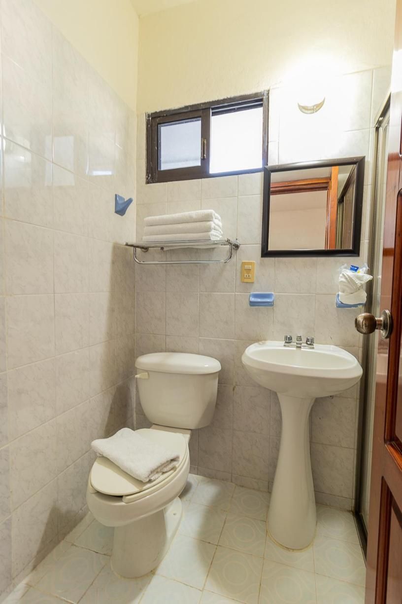 A bathroom with a toilet, sink, and a towel rack.