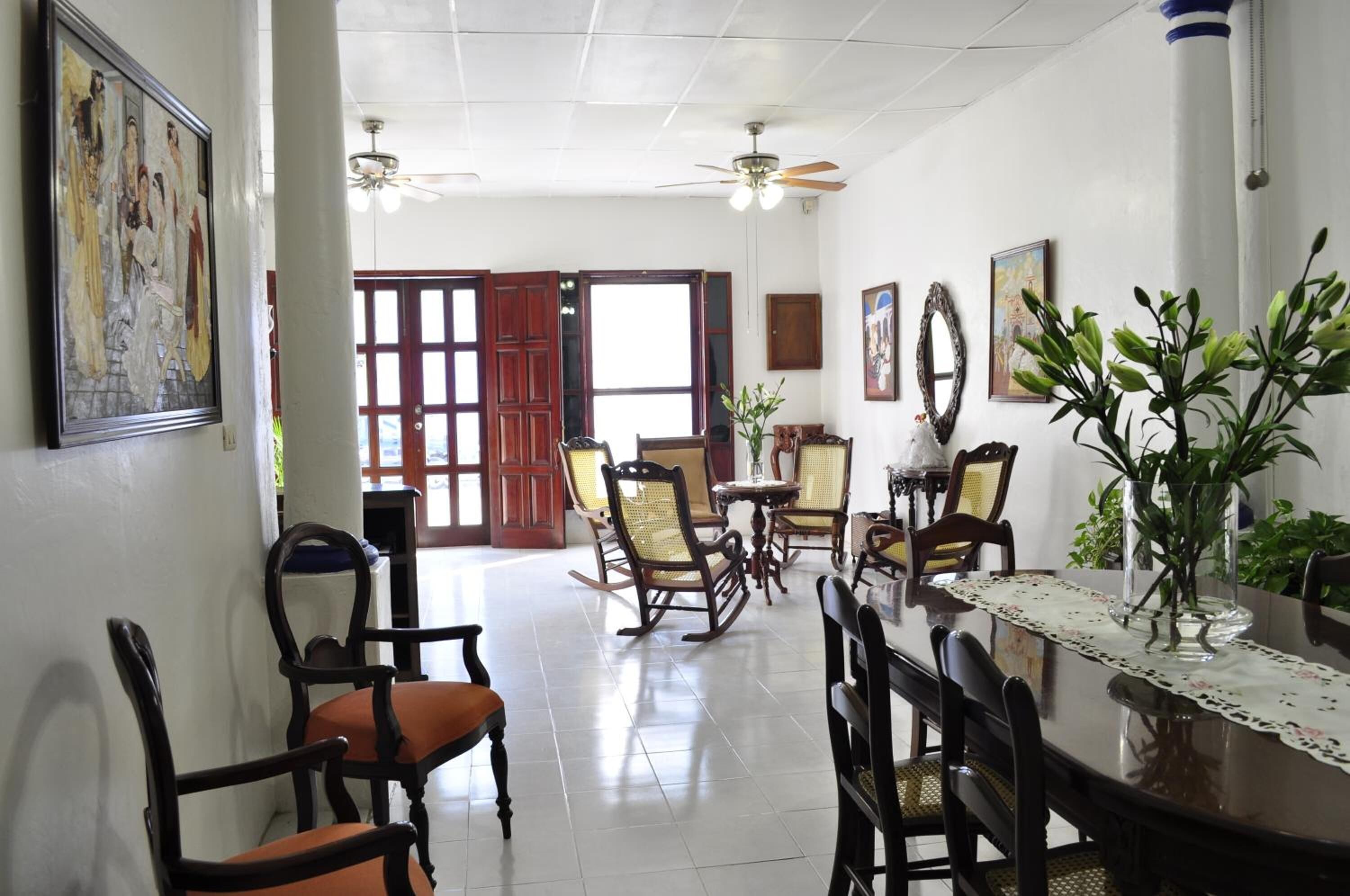 Un coin repas avec des chaises en bois, une table en verre et un ventilateur de plafond.