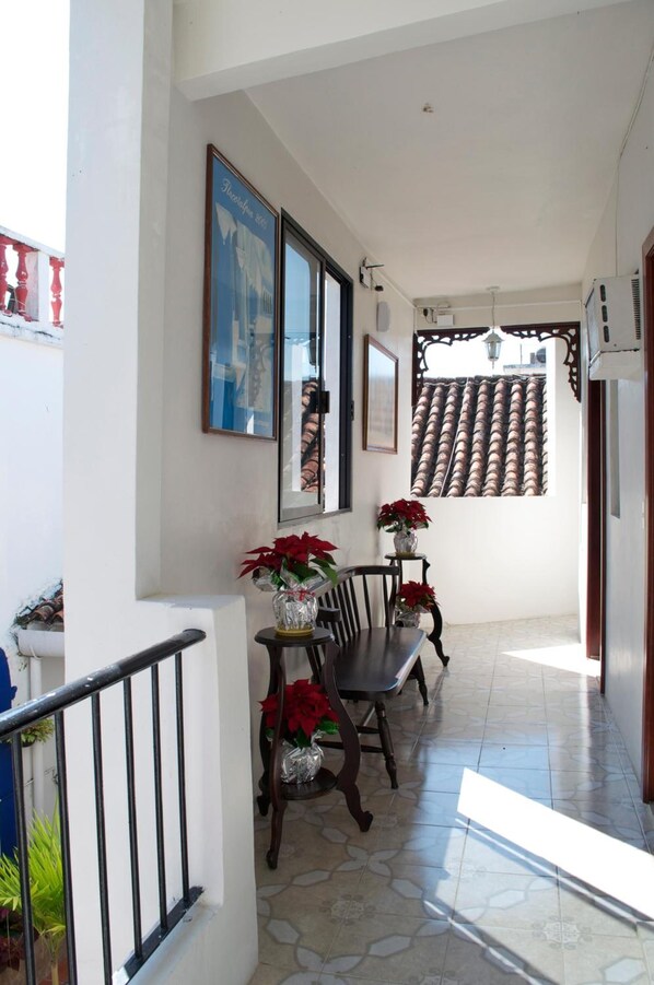 A hallway with a staircase, a dining area with chairs and a table, and a tiled floor.