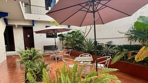 A courtyard with outdoor seating, potted plants, and a large umbrella.