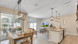A spacious kitchen with a central island, pendant lighting, and a large clock on the wall.