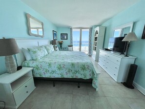 Un dormitorio con cama, mesita de noche, cómoda, televisor y vista al océano.