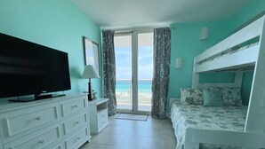 A bedroom with a television, a dresser, a bunk bed, and a view of the beach. - Sabine 6E- Sleeps 6 Gulf View Pensacola Beach Condo (Pensacola Beach)