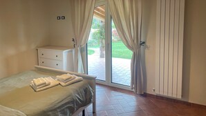 Une chambre à coucher avec un lit, une table de chevet, une commode et une fenêtre avec des rideaux.
