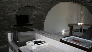 Cocina con paredes de piedra, microondas, televisor y una bandeja con diseño floral.