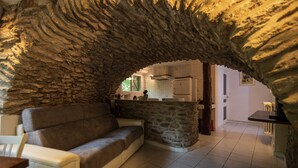 Una sala de estar acogedora con un arco de piedra que conduce a una cocina.