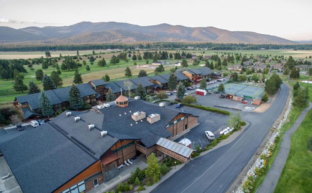 A lodge with multiple cabins, a parking area, and a large open field in the background.