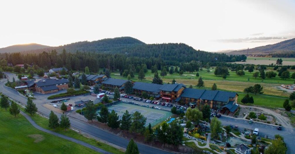 A lodge with multiple buildings, a parking lot, and a tennis court.