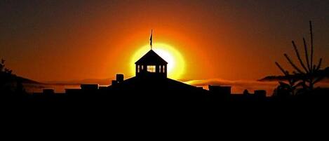 La silhouette d’un bâtiment surmonté d’un drapeau, se détachant sur un coucher de soleil.