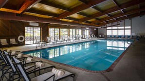 An indoor swimming pool with multiple lounge chairs and a wooden ceiling. - Stoneridge Resort (Blanchard)