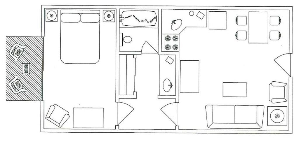 A floor plan of a hotel room with a bed, a desk, a chair, a small table, a sofa, and a bathroom with a toilet and sink.
