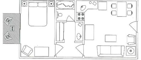 A floor plan of a hotel room with a bed, a desk, a chair, a small table, a sofa, and a bathroom with a toilet and sink.