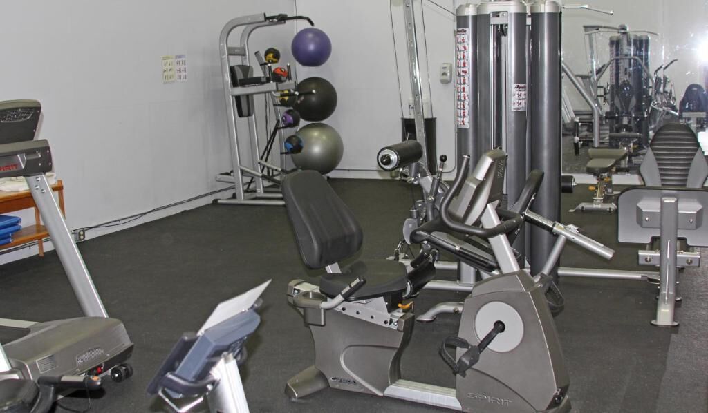 Ett gym med träningsutrustning, inklusive löpband, crosstrainer och styrketräningsmaskiner.