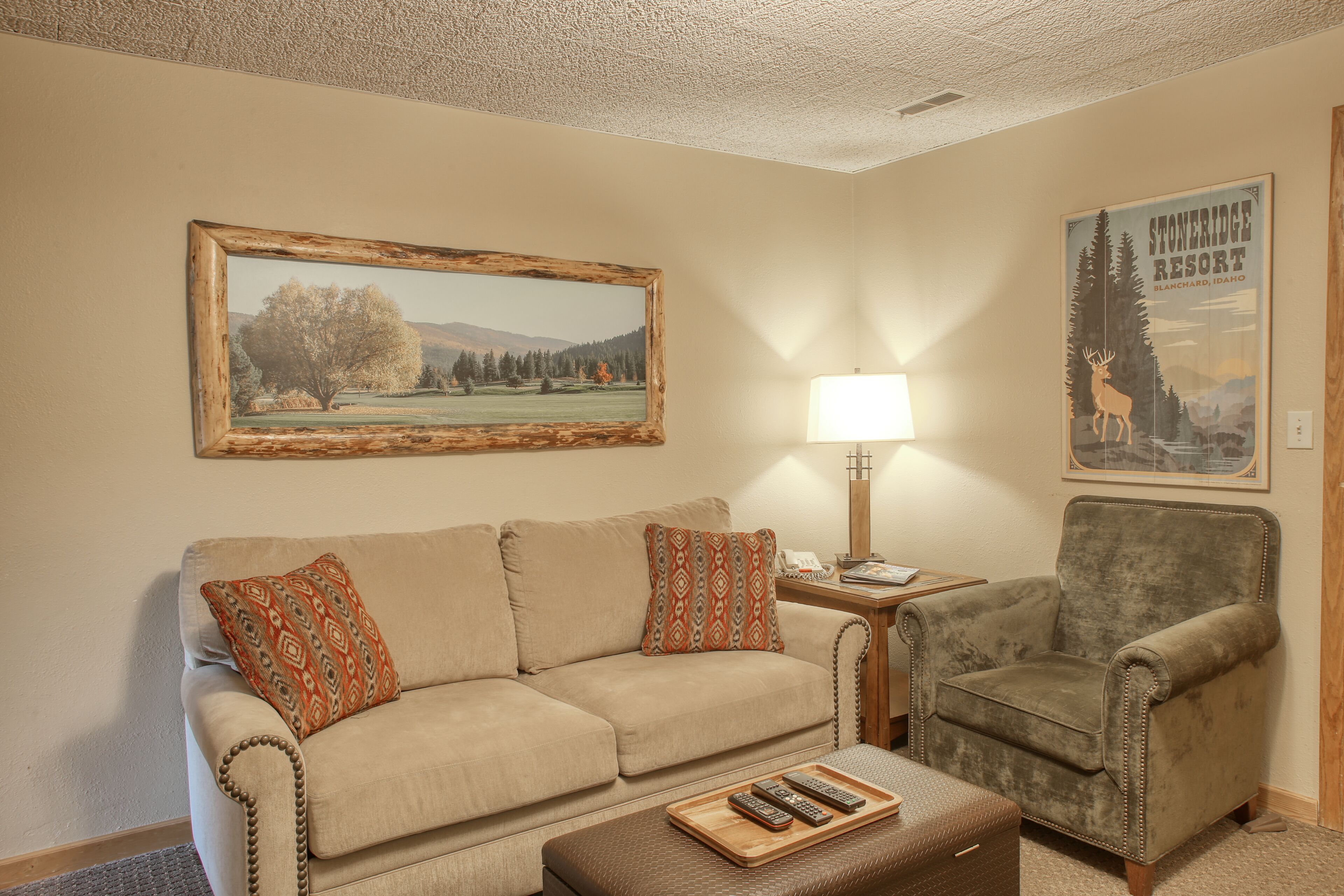A living room with a beige sofa, a wooden coffee table, a lamp, and a framed picture on the wall.