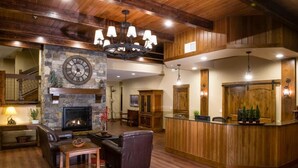 A spacious lobby with a stone fireplace, leather seating, a wooden reception desk, and a large clock on the wall. - Stoneridge Resort (Blanchard)