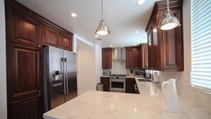 A modern kitchen with dark wood cabinets, stainless steel appliances, and a marble countertop. - Beverly Hills Luxury Condo, 5% Discounts on monthly bookings. (Los Angeles)