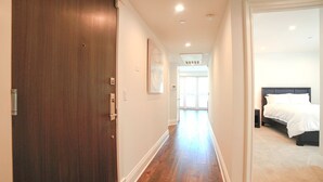 A hallway leading to a bedroom with a wooden door, a white wall, and a carpeted floor. - Beverly Hills Luxury Condo, 5% Discounts on monthly bookings. (Los Angeles)