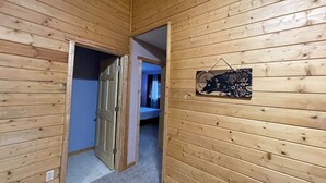 A wooden-paneled hallway with a door leading to a bedroom. - Willow Forest Cabin with Sauna, Pet and Family Friendly (Willow)
