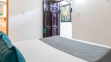 Ein Hotelzimmer mit Bett, Tür und einem Bild an der Wand.
