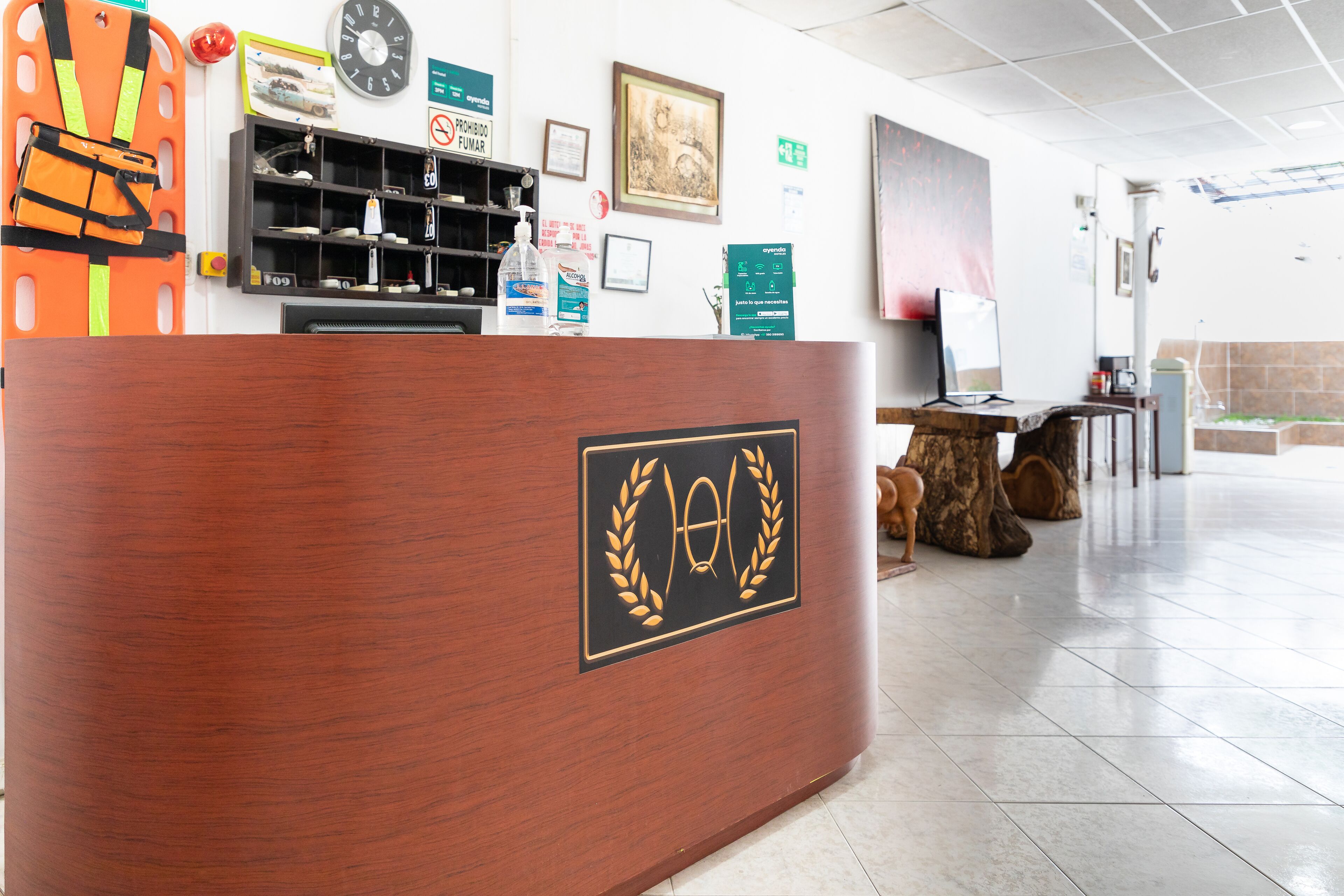 A reception desk with a logo, a clock, and a shelf with various items.