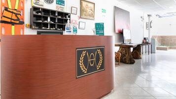 A reception desk with a logo, a clock, and a shelf with various items.