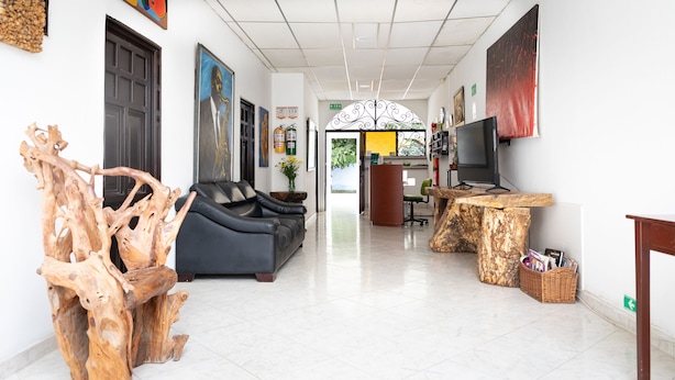 Eine großzügige Lobby mit einer schwarzen Ledersofa, einem Holztisch und einer großen Holzskulptur.