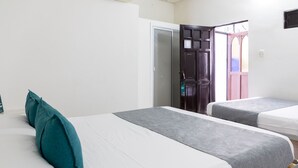Ein Hotelzimmer mit zwei Einzelbetten, einem Kleiderschrank und einer Tür zu einem Balkon.