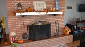 Une cheminée avec un mur en briques, une horloge et des décorations de saison.