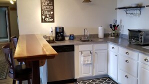 Une cuisine moderne avec des meubles blancs, une table à manger en bois, une machine à café et un grille-pain.