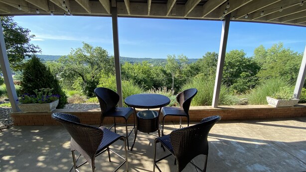 Une terrasse extérieure dotée d'une pergola, de meubles en osier et offrant une vue sur le paysage.
