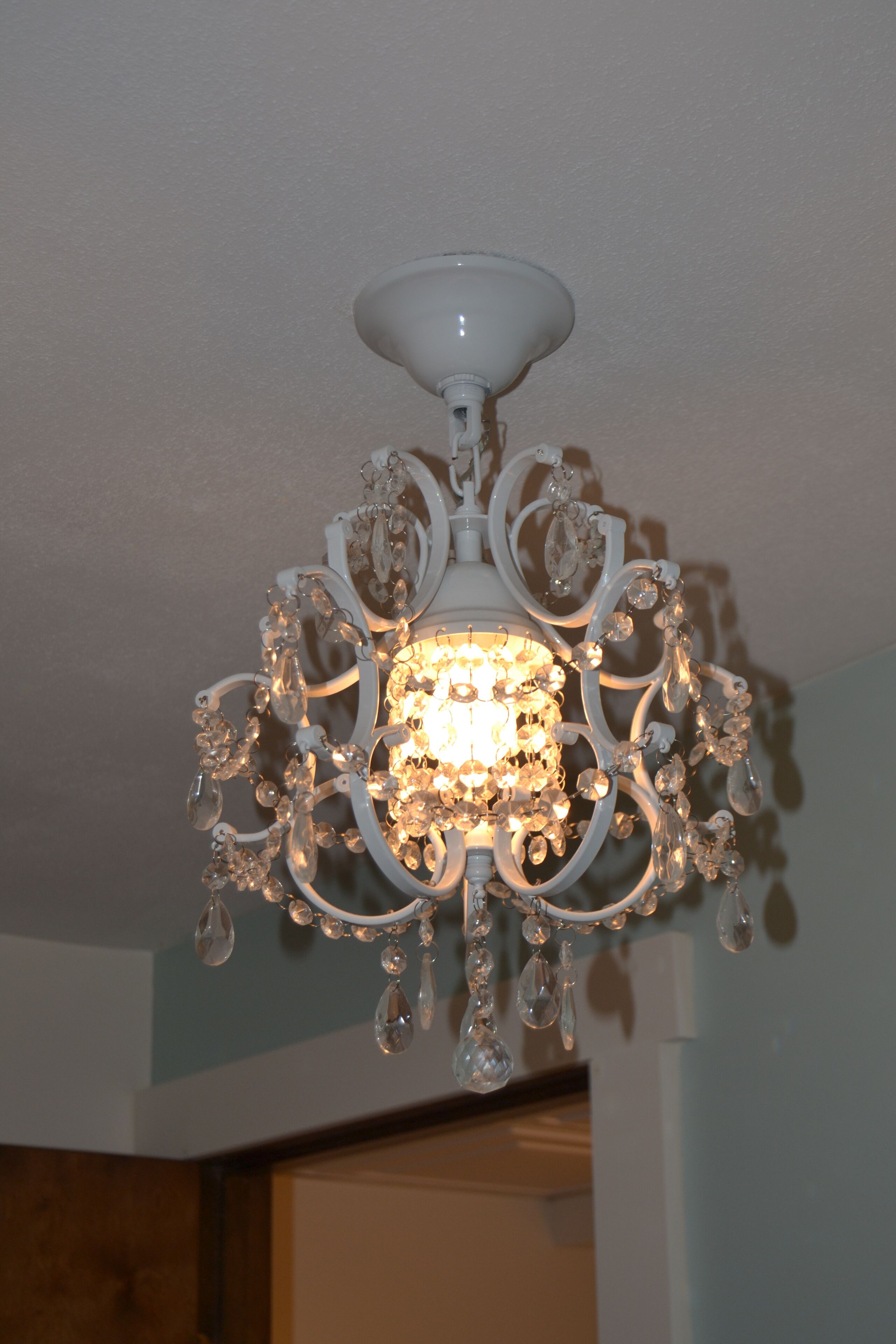 A chandelier with multiple crystal elements and a white base.