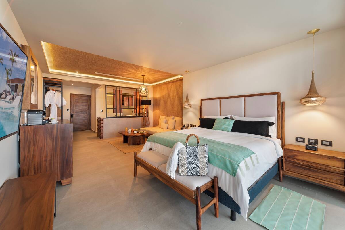 Une chambre d’hôtel moderne avec un grand lit, des tables de chevet, un bureau et un miroir.
