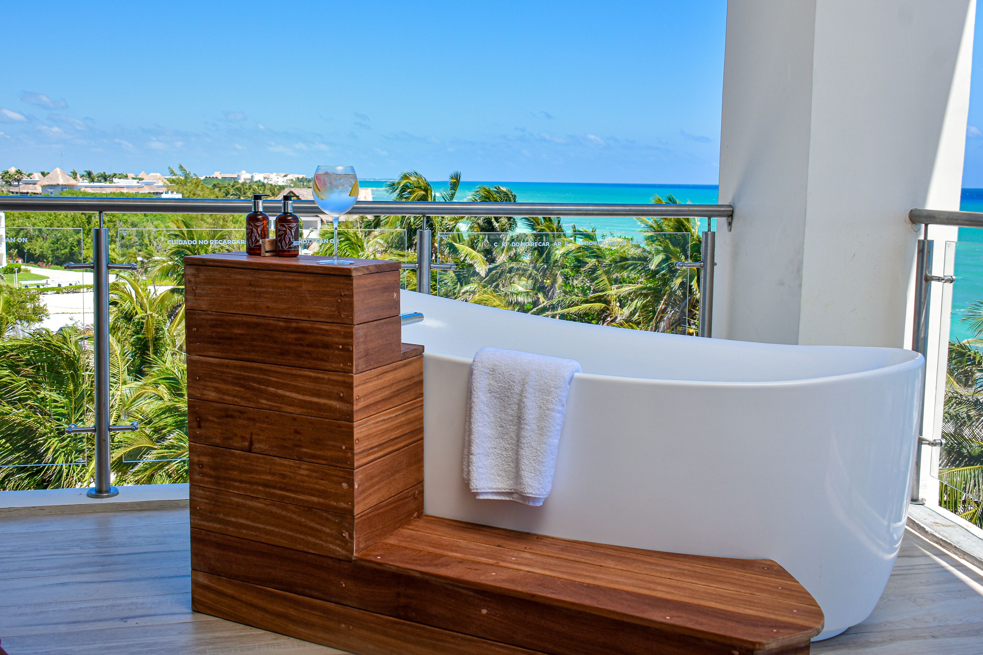 Une salle de bain moderne avec une baignoire, un meuble-lavabo en bois et une vue sur l’océan.