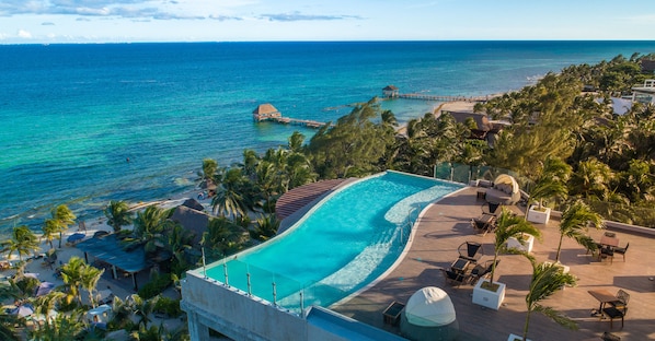 Un resort con una amplia piscina infinita, una playa y un muelle.