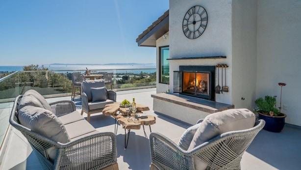 A balcony with wicker furniture, a fireplace, and a clock on the wall.