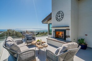 A balcony with wicker furniture, a fireplace, and a clock on the wall.