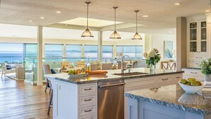 A spacious kitchen with a large island, stainless steel appliances, and a view of the ocean.