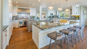 A spacious kitchen with a large island, modern appliances, and pendant lighting.