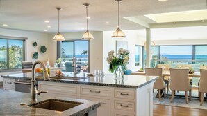 A modern kitchen with a large island, stainless steel appliances, and pendant lighting.