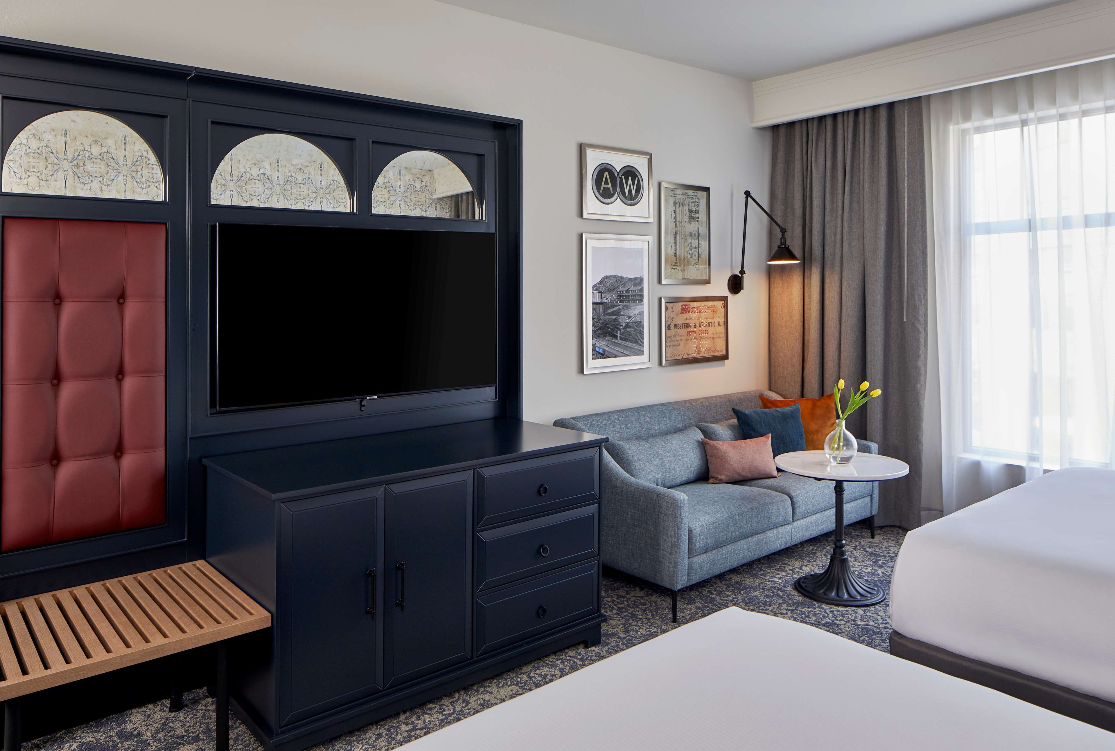Une chambre d’hôtel avec un grand lit, un canapé, une télévision, une armoire et une petite table sur laquelle se trouve un vase.