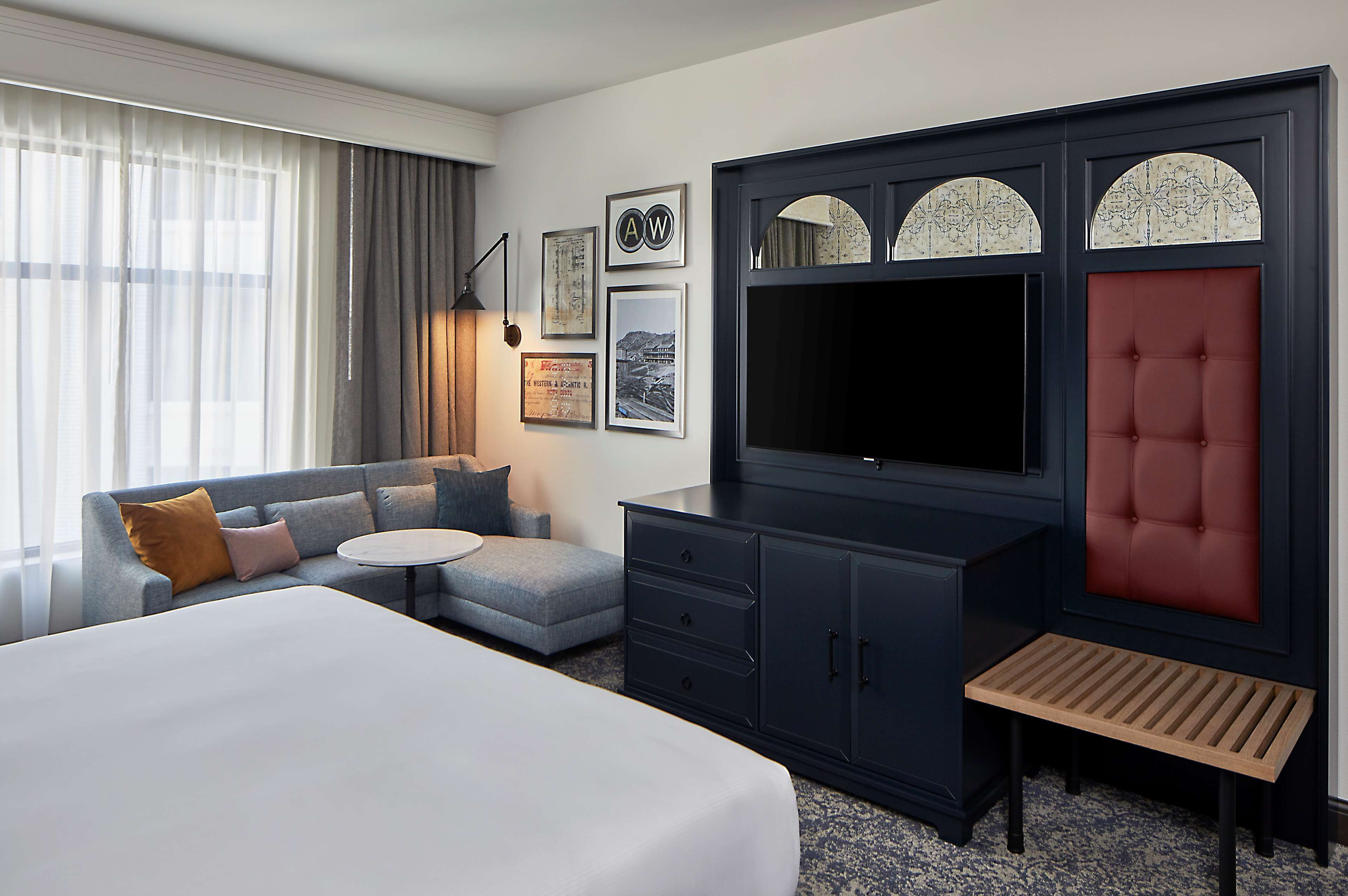 A hotel room with a large bed, a sofa, a desk, and a TV.