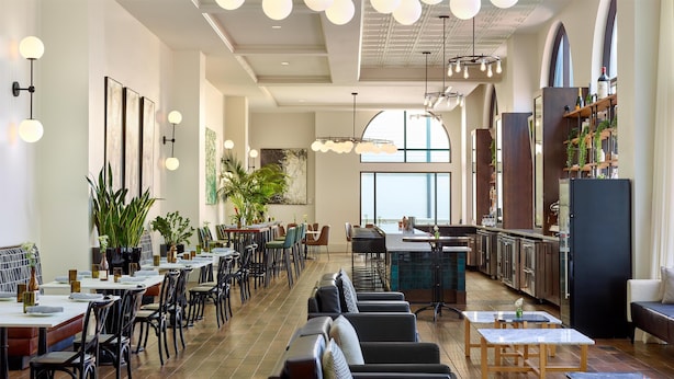 A spacious restaurant with high ceilings, modern lighting, and a view of the city.