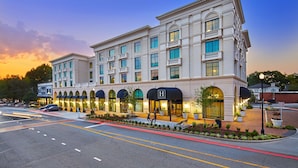 A large, multi-story hotel with a classical architectural style, featuring arched windows and a central entrance with a black awning.