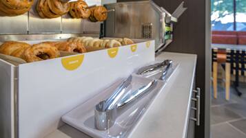 A breakfast station with a variety of pastries and a tray of utensils.