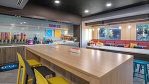 Una barra de desayuno con asientos, una máquina de café y vistas al exterior.