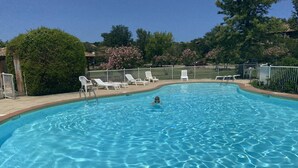 Une piscine à l’eau d’un bleu cristallin, entourée de chaises longues blanches et délimitée par une clôture.
