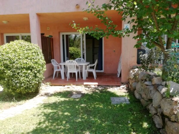 A patio with a table and chairs, a small garden, and a stone wall. - A wonderful residence on the island of Corsica: Marina di Pinarello (Zonza)