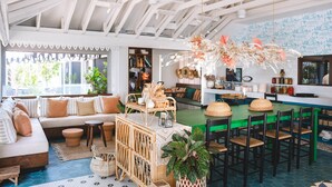 A spacious living area with a high ceiling, a green dining table, and a bar area.